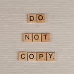 Close-up of wooden tiles spelling 'Do Not Copy' on a textured surface.