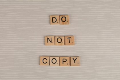 Close-up of wooden tiles spelling 'Do Not Copy' on a textured surface.