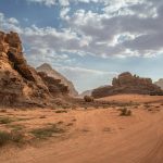 Scenic desert landscape with rock formations and cloudy sky in Wadi Rum, Jordan.