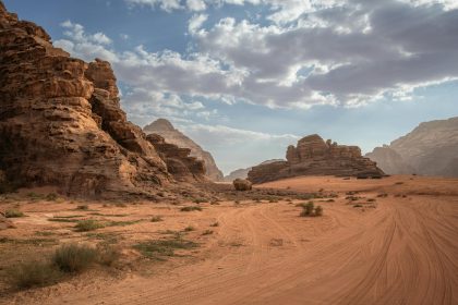 Scenic desert landscape with rock formations and cloudy sky in Wadi Rum, Jordan.