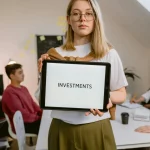 Young professional holding tablet in team meeting focused on investments.