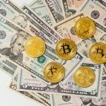 A selection of Bitcoin coins placed on US dollar bills representing cryptocurrency and traditional money.