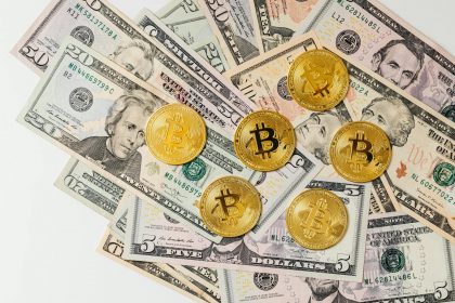 A selection of Bitcoin coins placed on US dollar bills representing cryptocurrency and traditional money.